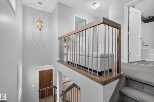 Wood-finish handrail with metal balusters, carpeted stairs, and a built-in light fixture - 11018 122 Street Nw, Edmonton, AB - Indoor Photo Showing Other Room