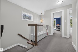 Carpeted upper landing with a contemporary open railing, built-in bench, and a modern chandelier - 