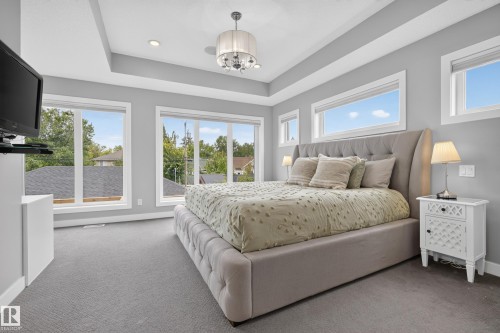 Tray ceiling with a decorative chandelier, recessed lighting, and multiple windows - 11018 122 Street Nw, Edmonton, AB - Indoor Photo Showing Bedroom