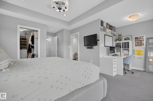 Tray ceiling with recessed lighting, built-in closet organization system, carpeted flooring, wall-mounted television, and a built-in desk unit - 11018 122 Street Nw, Edmonton, AB - Indoor Photo Showing Bedroom