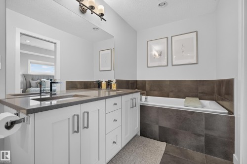 Dual vanity with undermount sinks, stone countertop, and contemporary faucets - 11018 122 Street Nw, Edmonton, AB - Indoor Photo Showing Bathroom