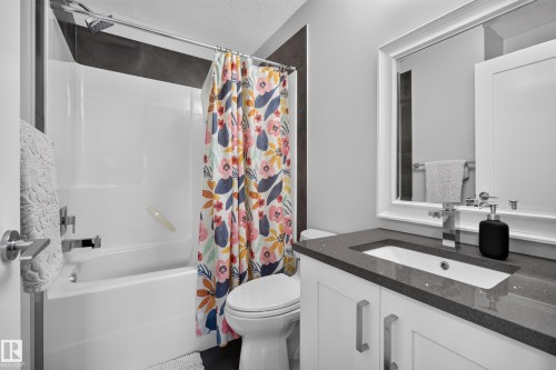 White vanity with brushed nickel hardware, integrated sink, and dark quartz countertop - 11018 122 Street Nw, Edmonton, AB - Indoor Photo Showing Bathroom