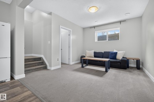 Well-lit living area featuring recessed lighting, a window, grey carpeting, and wood-finish flooring - 11018 122 Street Nw, Edmonton, AB - Indoor