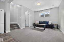 Well-lit living area featuring recessed lighting, a window, grey carpeting, and wood-finish flooring - 