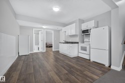 Compact kitchen featuring white cabinetry, dark countertops, and white appliances including a refrigerator, range, and microwave - 
