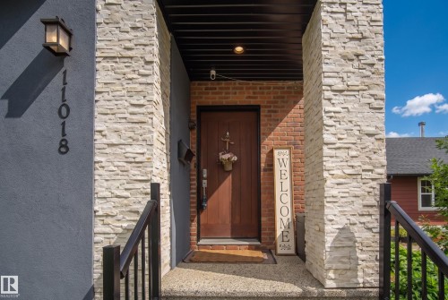 Stucco exterior with stone accents, dark wood entry door, and dark metal railings - 11018 122 Street Nw, Edmonton, AB - Outdoor