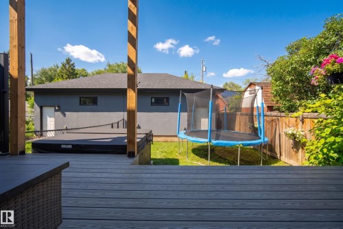 Expansive outdoor deck with gray wood-finish flooring, featuring a built-in hot tub, and a manicured lawn - 11018 122 Street Nw, Edmonton, AB - Outdoor With Deck Patio Veranda