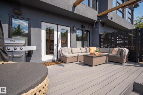 Expansive outdoor deck featuring wood-finish decking, a stucco exterior, and black-framed windows - 11018 122 Street Nw, Edmonton, AB - Outdoor With Deck Patio Veranda With Exterior