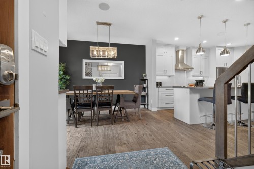 Spacious interior featuring wood-finish flooring, a contemporary kitchen with white cabinetry, stainless steel appliances, and a kitchen island with seating - 11018 122 Street Nw, Edmonton, AB - Indoor