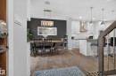 Spacious interior featuring wood-finish flooring, a contemporary kitchen with white cabinetry, stainless steel appliances, and a kitchen island with seating - 11018 122 Street Nw, Edmonton, AB  - Indoor 