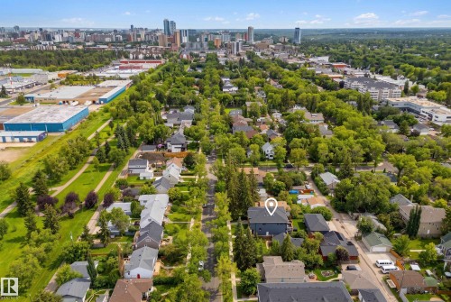 Residential property in a tree-lined neighborhood, featuring a prominent building with a light-colored roof - 11018 122 Street Nw, Edmonton, AB - Outdoor With View