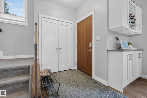 Wood entry door, built-in white cabinetry with a wine rack, and a gray countertop - 11018 122 Street Nw, Edmonton, AB - Indoor Photo Showing Other Room