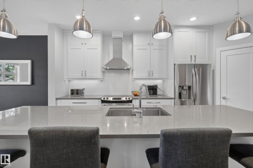 Kitchen featuring white shaker cabinetry, stainless steel appliances, a large island with an undermount sink, and pendant lighting - 11018 122 Street Nw, Edmonton, AB - Indoor Photo Showing Kitchen With Upgraded Kitchen