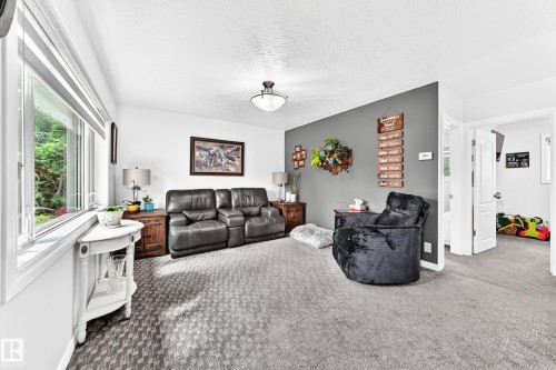 Expansive windows, carpeted flooring, white walls, and a contemporary ceiling light fixture - 10524 128 Avenue Nw, Edmonton, AB - Indoor Photo Showing Living Room