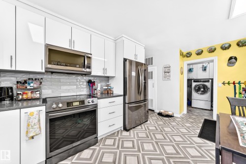 White shaker-style cabinetry with stainless steel appliances, gray countertops, and a patterned flooring - 10524 128 Avenue Nw, Edmonton, AB - Indoor Photo Showing Kitchen With Upgraded Kitchen