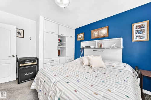 Built-in white cabinetry with open shelving, recessed lighting, wall-mounted headboard with integrated shelving, and a flush-mount ceiling light - 10524 128 Avenue Nw, Edmonton, AB - Indoor Photo Showing Bedroom