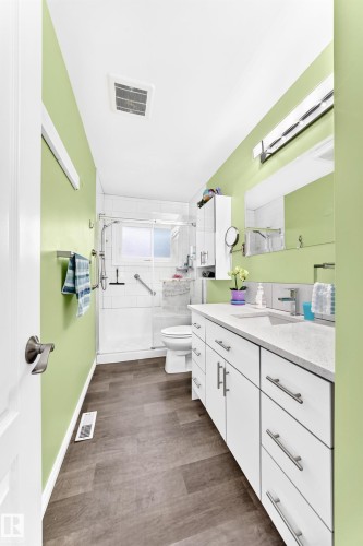 Wood-finish flooring with a white vanity featuring a light-toned countertop - 10524 128 Avenue Nw, Edmonton, AB - Indoor Photo Showing Bathroom