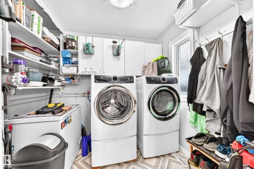 Laundry area featuring front-load washer and dryer, white cabinetry, built-in shelving, and a single window - 10524 128 Avenue Nw, Edmonton, AB - Indoor Photo Showing Laundry Room