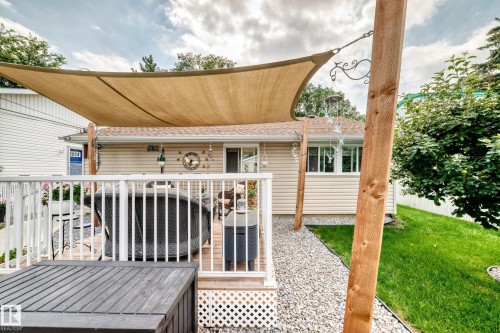 Deck with white railings, a tan shade sail, and a gravel pathway - 10524 128 Avenue Nw, Edmonton, AB - Outdoor With Deck Patio Veranda