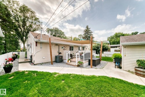 Backyard featuring a wood deck with a shade sail, gravel landscaping, and a concrete pathway - 10524 128 Avenue Nw, Edmonton, AB - Outdoor