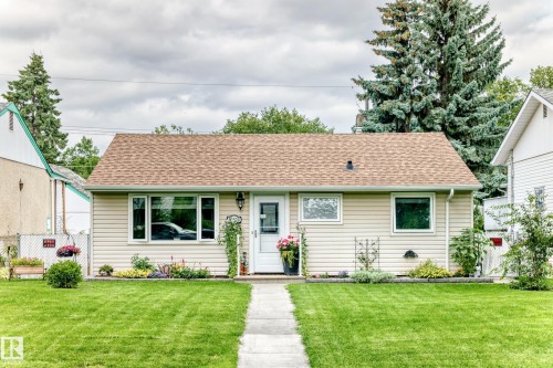 Ranch-style residence featuring a tan shingle roof, beige siding, white trim windows, and a paved walkway - 10524 128 Avenue Nw, Edmonton, AB - Outdoor