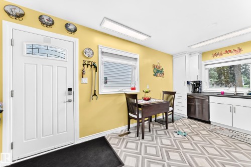 Kitchen space featuring white cabinetry, dark countertops, a stainless steel dishwasher, and patterned flooring - 10524 128 Avenue Nw, Edmonton, AB - Indoor