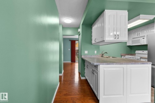 Kitchen featuring white cabinetry, a double basin sink, and a built-in microwave - 152 Woodstock Nw, Edmonton, AB - Indoor Photo Showing Other Room