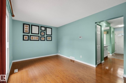 Hardwood flooring, light blue wall paint, white trim, and a white ceiling - 152 Woodstock Nw, Edmonton, AB - Indoor Photo Showing Other Room