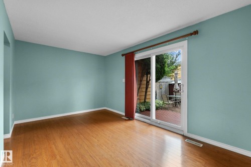 Sliding glass door, wood-finish flooring, light blue wall paint, white trim, outdoor patio - 152 Woodstock Nw, Edmonton, AB - Indoor Photo Showing Other Room