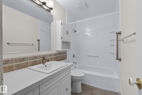 White vanity with a single basin sink, bronze-finish faucet, and a large wall-mounted mirror - 152 Woodstock Nw, Edmonton, AB - Indoor Photo Showing Bathroom