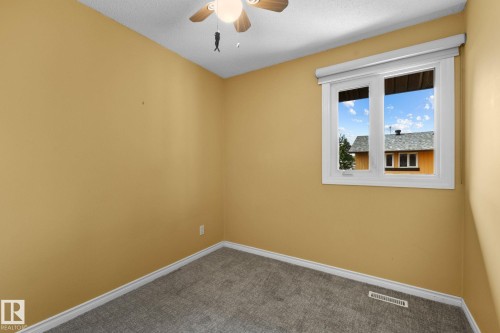 Textured carpeting, light-toned walls, and a ceiling fan with integrated lighting - 152 Woodstock Nw, Edmonton, AB - Indoor Photo Showing Other Room