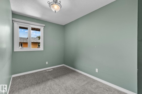 Neutral paint palette with a single window, overhead decorative light fixture, and grey carpet flooring - 152 Woodstock Nw, Edmonton, AB - Indoor Photo Showing Other Room