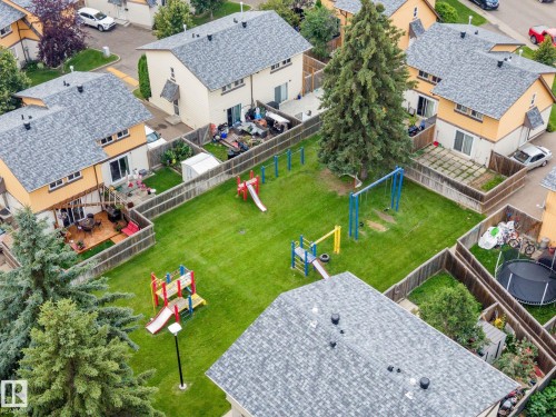 Expansive communal green space featuring a manicured lawn and playground equipment - 152 Woodstock Nw, Edmonton, AB - Outdoor With Deck Patio Veranda