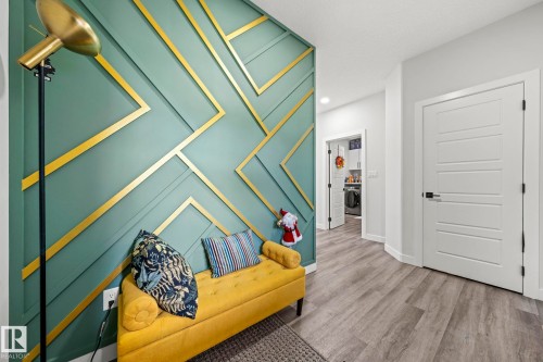 Accent wall with geometric gold detailing, contemporary five-panel interior doors, and wood-finish flooring - 16128 31 Avenue Sw, Edmonton, AB - Indoor Photo Showing Other Room