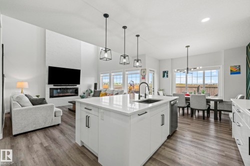 Spacious living area featuring high ceilings, wood-finish flooring, and a modern fireplace - 16128 31 Avenue Sw, Edmonton, AB - Indoor Photo Showing Kitchen With Upgraded Kitchen