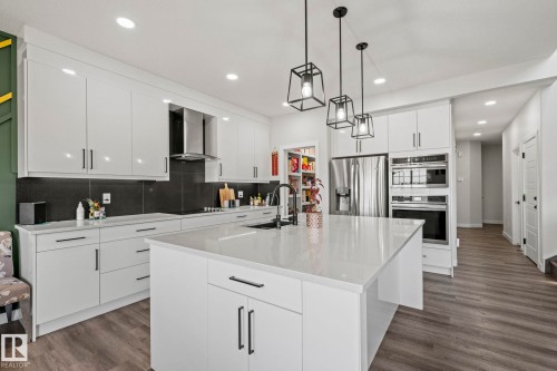 Kitchen featuring a large island, white cabinetry, dark backsplash, stainless steel appliances, and recessed lighting - 16128 31 Avenue Sw, Edmonton, AB - Indoor Photo Showing Kitchen With Upgraded Kitchen