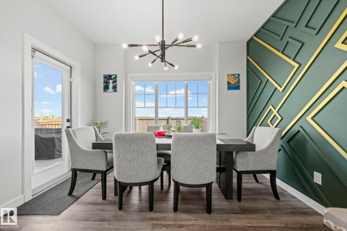 Wood-finish flooring, accent wall with geometric molding, modern sputnik chandelier, and a large window - 16128 31 Avenue Sw, Edmonton, AB - Indoor Photo Showing Dining Room