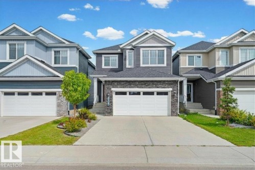 Contemporary exterior with dark siding and stone accents, featuring a two-car garage and a concrete driveway - 16128 31 Avenue Sw, Edmonton, AB - Outdoor With Facade