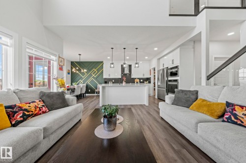 Wood-finish flooring throughout, with a spacious kitchen island featuring pendant lighting - 16128 31 Avenue Sw, Edmonton, AB - Indoor Photo Showing Living Room