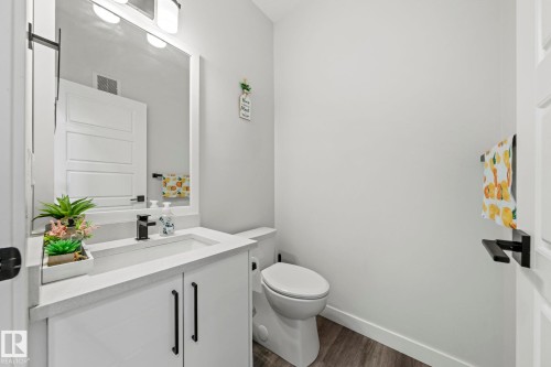White vanity with a rectangular sink, black hardware, and an overhead light fixture - 16128 31 Avenue Sw, Edmonton, AB - Indoor Photo Showing Bathroom