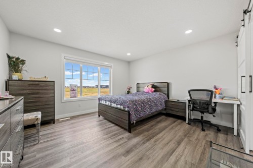 Spacious room featuring wood-finish flooring, recessed lighting, and a large multi-pane window - 16128 31 Avenue Sw, Edmonton, AB - Indoor Photo Showing Bedroom