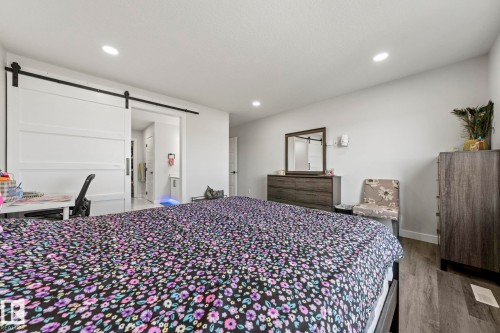 Recessed ceiling lighting, wood-finish flooring, and a white barn door - 16128 31 Avenue Sw, Edmonton, AB - Indoor Photo Showing Bedroom