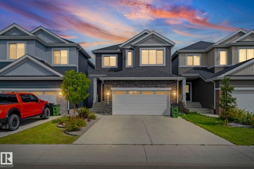Exterior featuring a two-car garage, stone and siding facade, concrete driveway, and front landscaping - 16128 31 Avenue Sw, Edmonton, AB - Outdoor With Facade