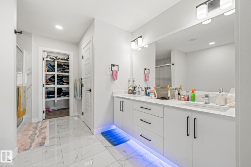 Double vanity with white cabinetry, integrated sinks, chrome faucets, and a large mirror - 16128 31 Avenue Sw, Edmonton, AB - Indoor Photo Showing Bathroom
