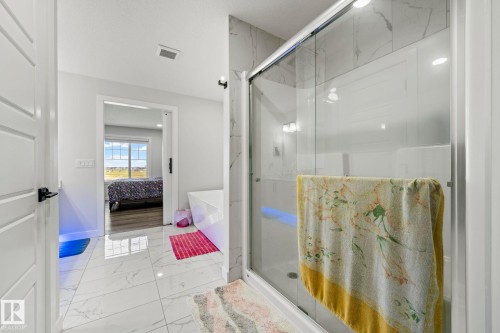 White marble-look floor tiling, built-in soaking tub, and enclosed shower with tile surround - 16128 31 Avenue Sw, Edmonton, AB - Indoor Photo Showing Bathroom