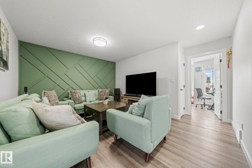 Accent wall with geometric paneling, wood-finish flooring, recessed ceiling lighting, and a flush-mount ceiling fixture - 16128 31 Avenue Sw, Edmonton, AB - Indoor Photo Showing Living Room