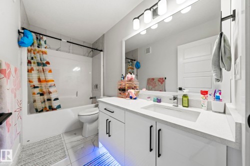 White vanity with integrated sink, rectangular mirror, and overhead vanity lighting - 16128 31 Avenue Sw, Edmonton, AB - Indoor Photo Showing Bathroom
