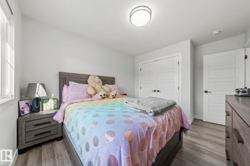 Recessed window with white trim, wood-finish flooring, flush mount ceiling light, and panel doors with matte black hardware - 16128 31 Avenue Sw, Edmonton, AB - Indoor Photo Showing Bedroom
