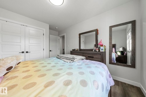 Recessed ceiling light fixture, white walls, wood-finish flooring, white paneled doors with dark hardware, and white trim - 16128 31 Avenue Sw, Edmonton, AB - Indoor Photo Showing Bedroom