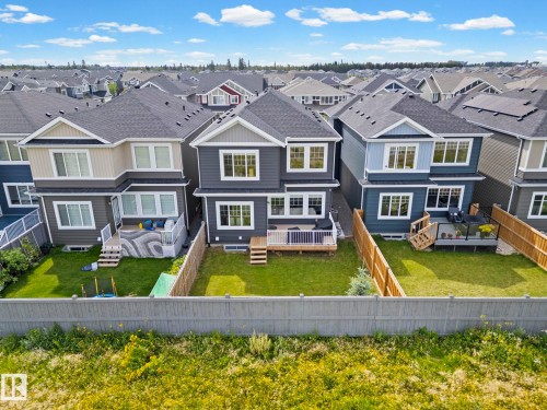 Backyard featuring a green lawn, wood fence, and a wooden deck with railing - 16128 31 Avenue Sw, Edmonton, AB - Outdoor With Facade